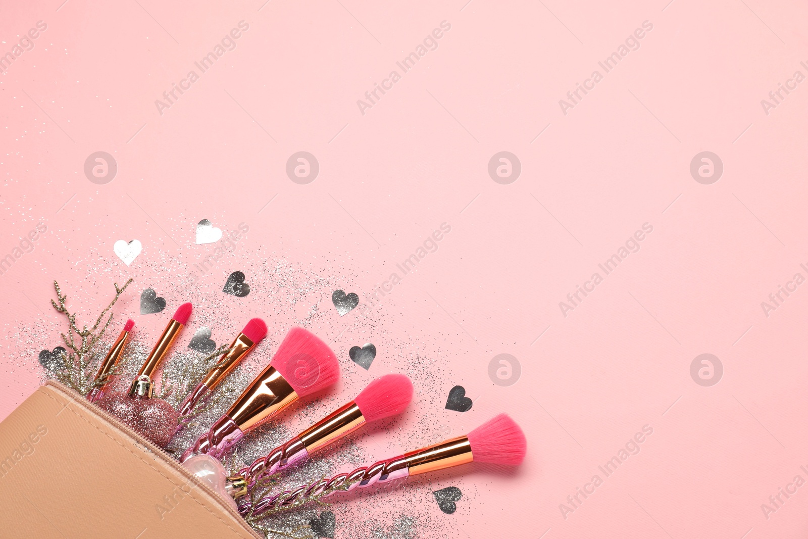 Photo of Cosmetic bag with makeup brushes and Christmas decor on pink background, top view. Space for text