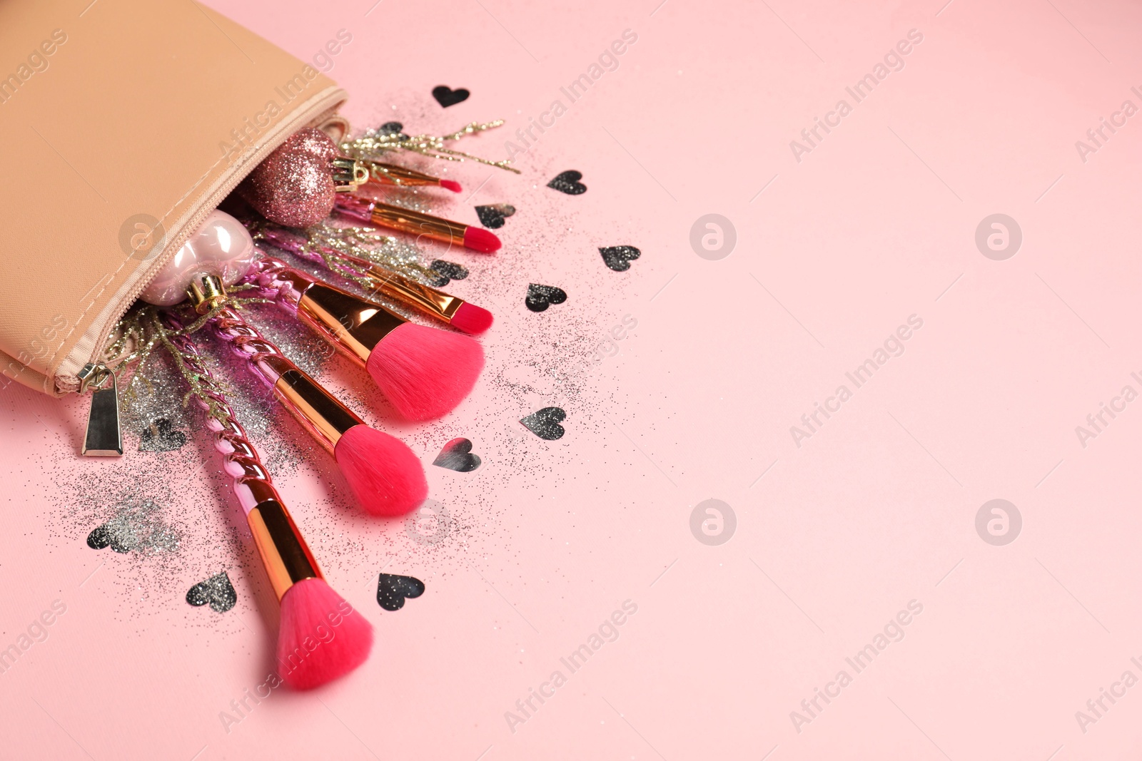 Photo of Cosmetic bag with makeup brushes and Christmas decor on pink background, space for text