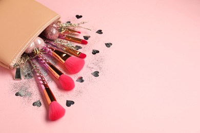 Photo of Cosmetic bag with makeup brushes and Christmas decor on pink background, space for text