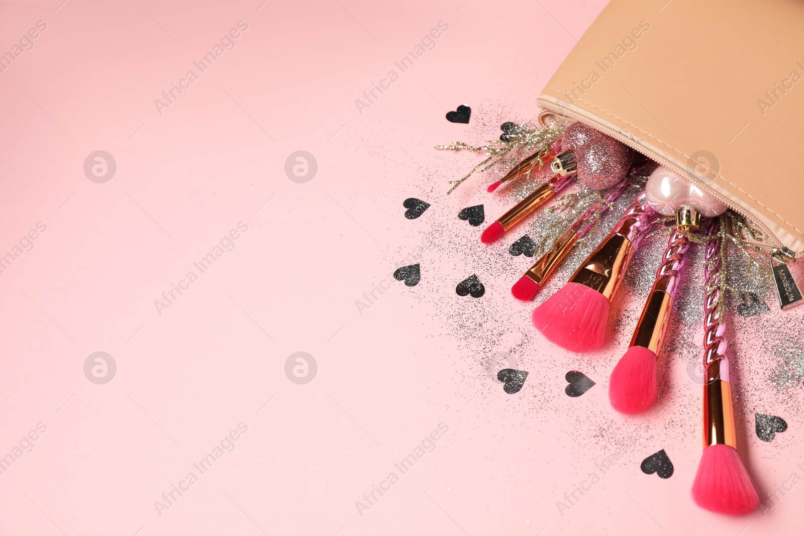 Photo of Cosmetic bag with makeup brushes and Christmas decor on pink background, above view. Space for text