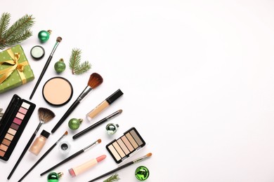 Photo of Different makeup brushes, decorative cosmetics and Christmas decor on white background, flat lay. Space for text