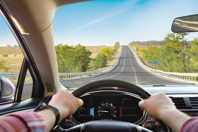 Man driving car on sunny morning, first-person view