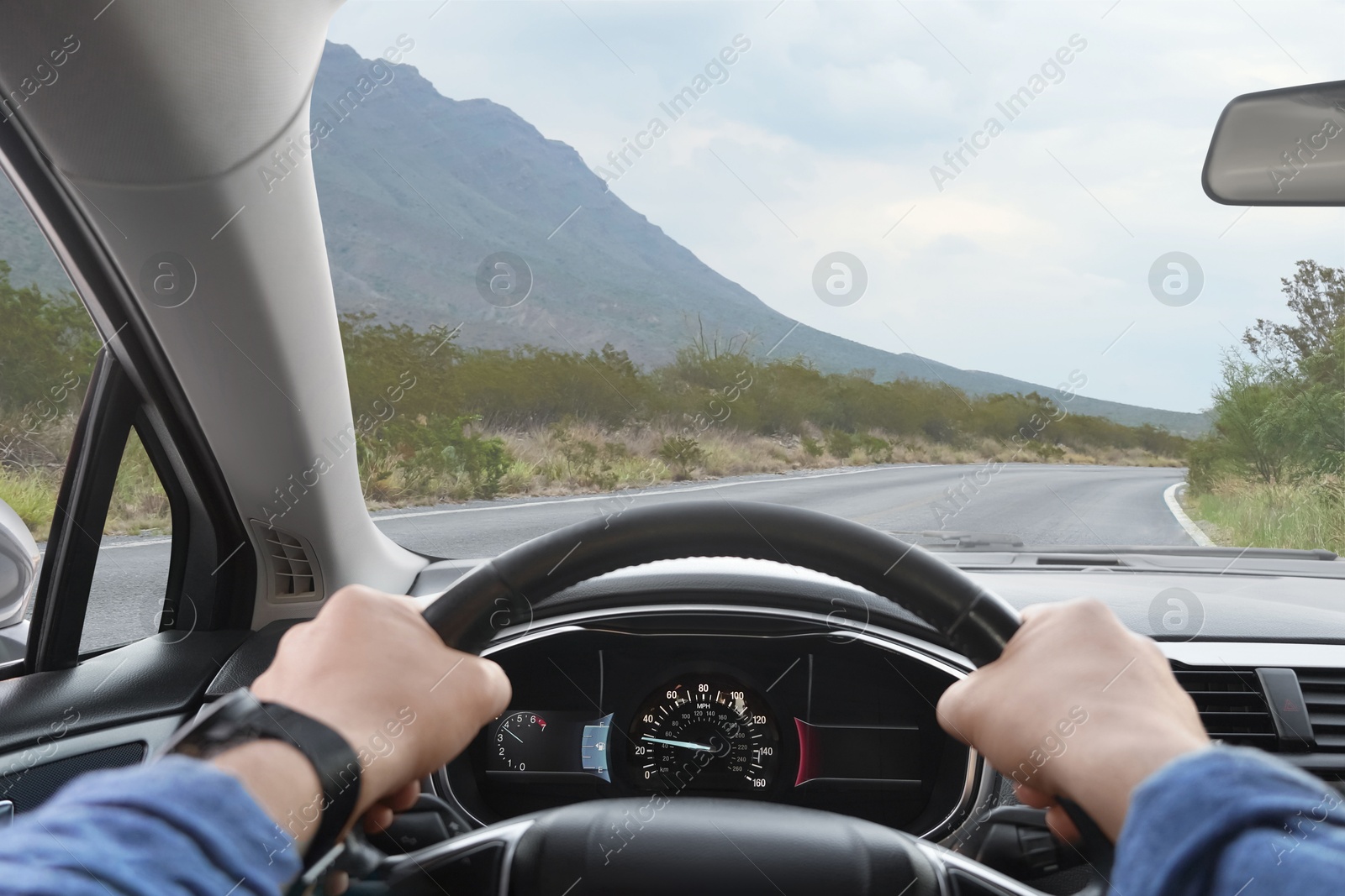 Image of Man driving car on mountain road, first-person view