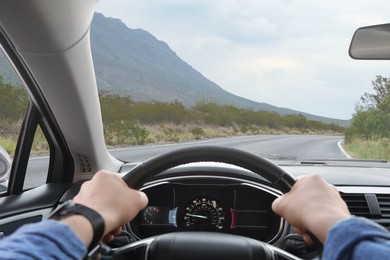 Image of Man driving car on mountain road, first-person view