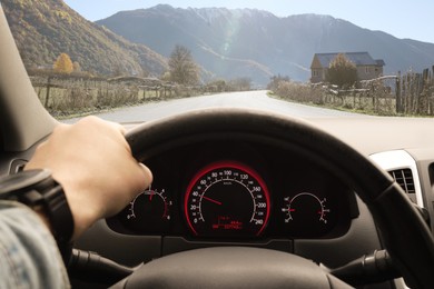 Image of Man driving car on mountain road, first-person view