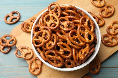 Photo of Tasty pretzel crackers on light blue wooden table, top view