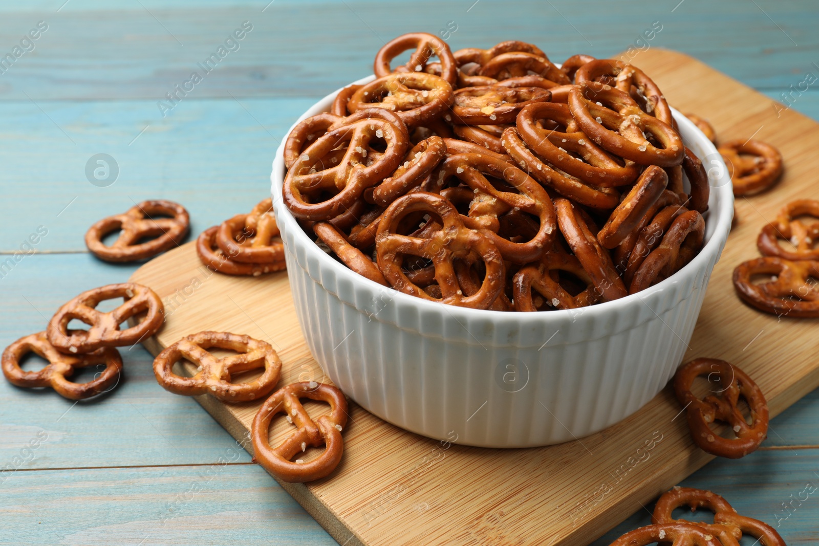 Photo of Tasty pretzel crackers on light blue wooden table, closeup