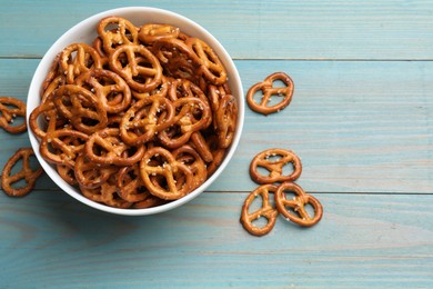 Photo of Tasty pretzel crackers on light blue wooden table, top view. Space for text