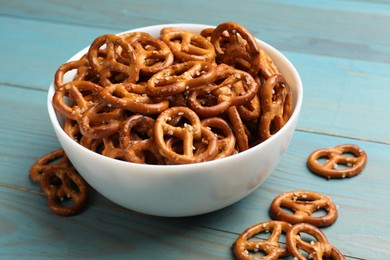 Photo of Tasty pretzel crackers on light blue wooden table, closeup