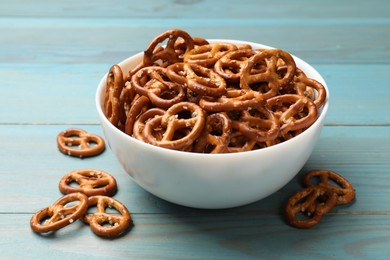 Photo of Tasty pretzel crackers on light blue wooden table, closeup