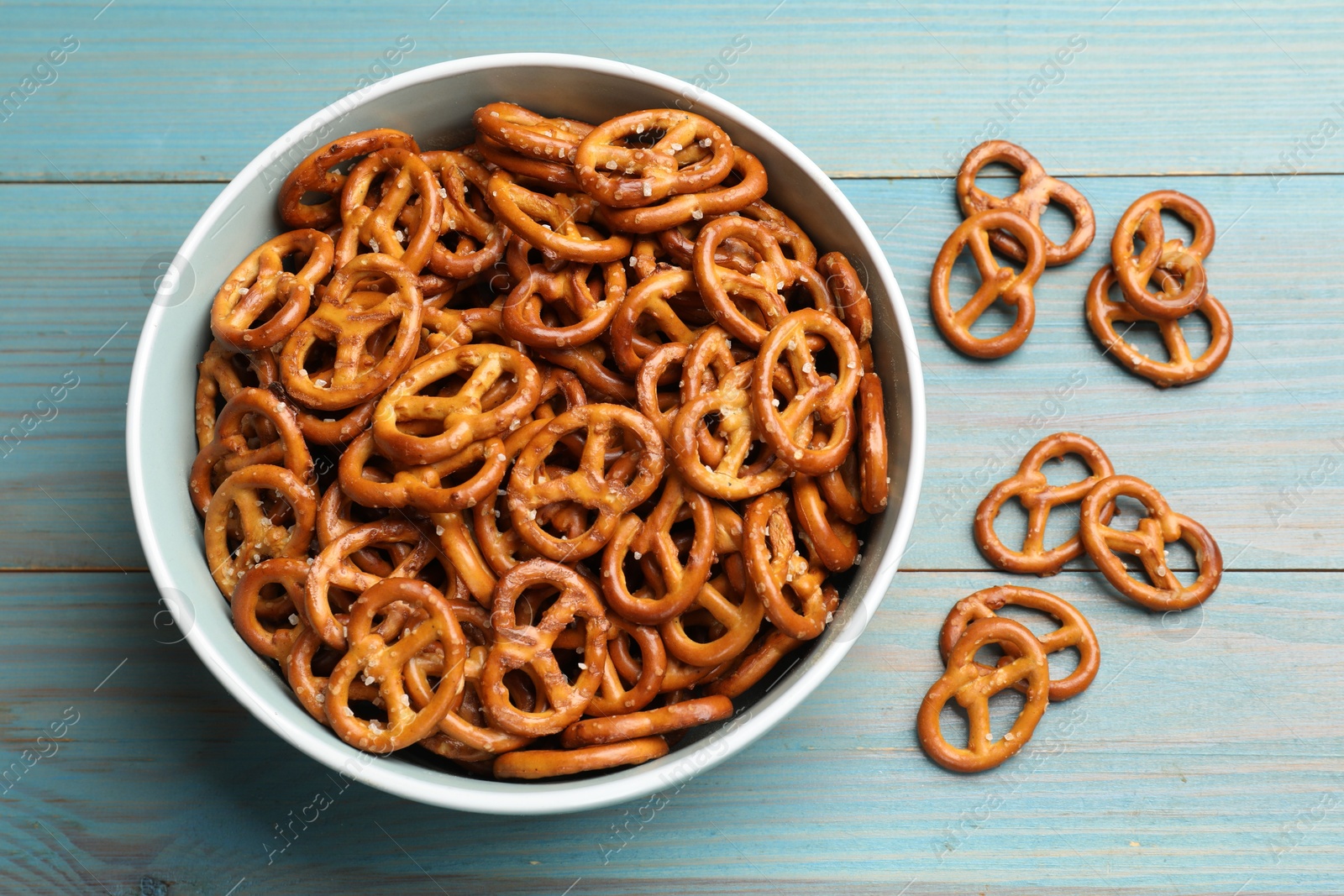 Photo of Tasty pretzel crackers on light blue wooden table, top view