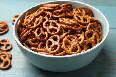 Photo of Tasty pretzel crackers on light blue wooden table, closeup