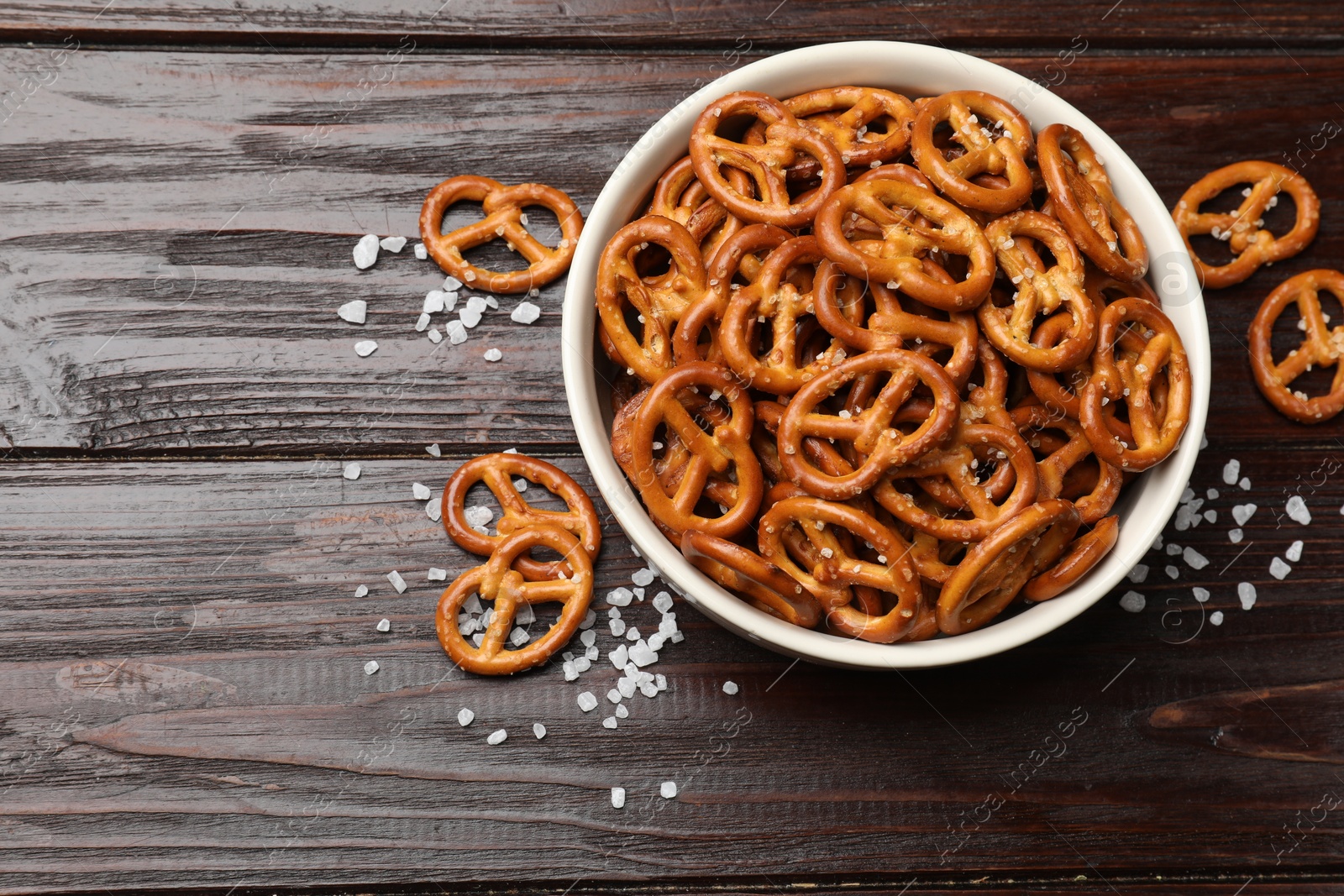 Photo of Tasty pretzel crackers with salt on wooden table, top view. Space for text