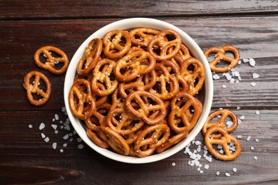 Photo of Tasty pretzel crackers with salt on wooden table, top view