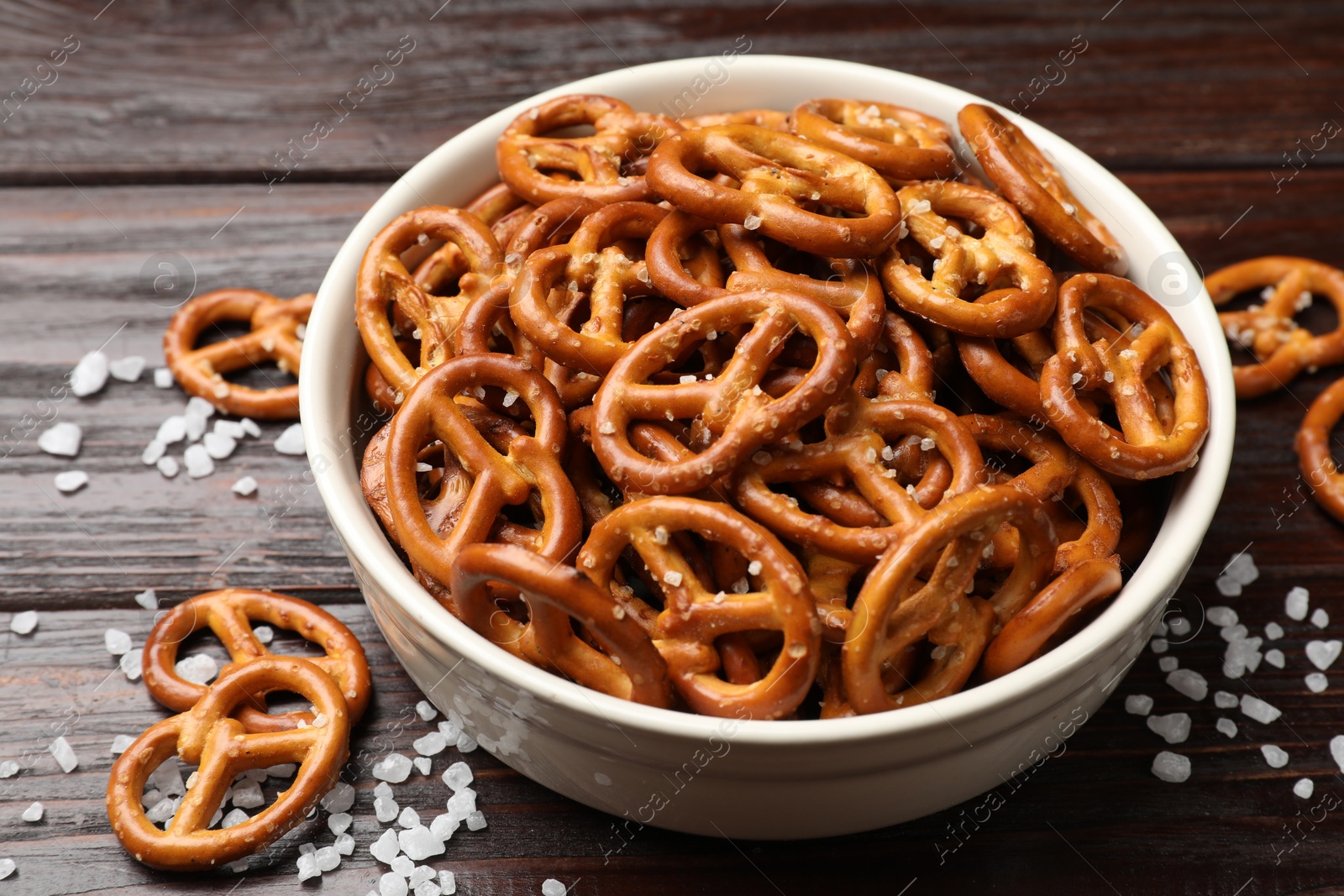 Photo of Tasty pretzel crackers with salt on wooden table, closeup