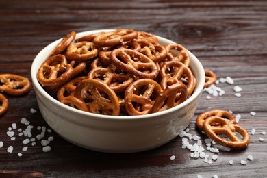 Photo of Tasty pretzel crackers with salt on wooden table, closeup