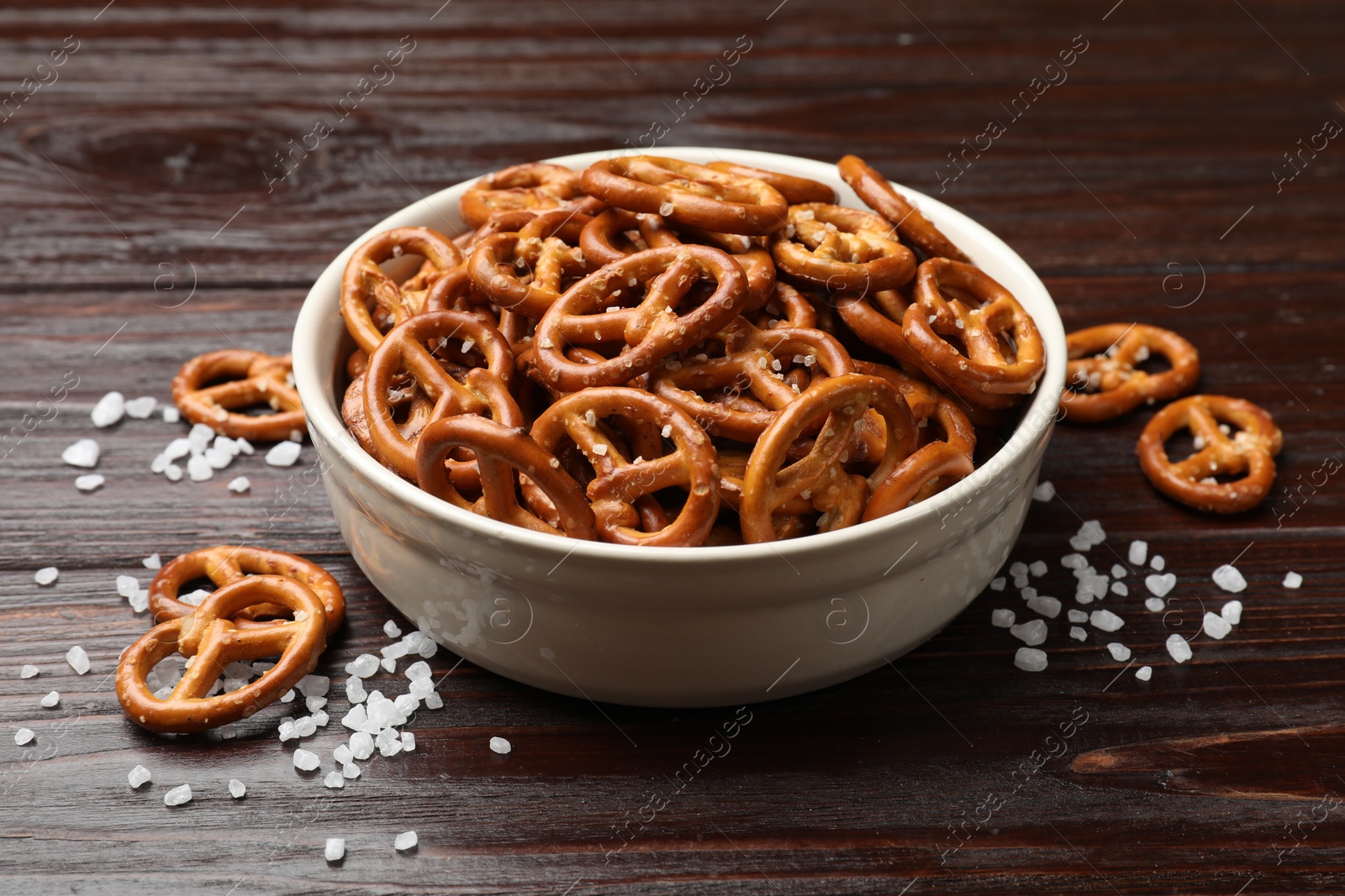 Photo of Tasty pretzel crackers with salt on wooden table, closeup