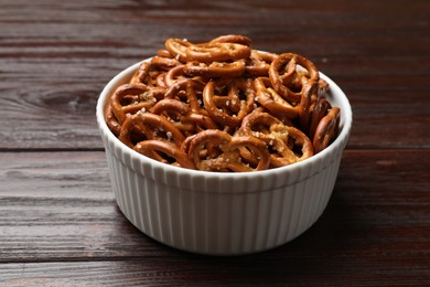 Photo of Tasty pretzel crackers in bowl on wooden table, closeup