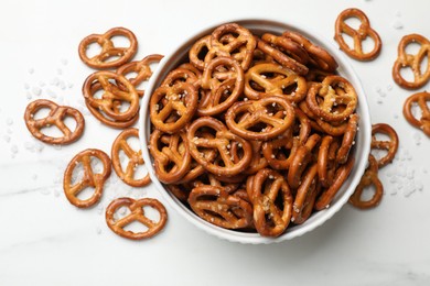 Photo of Tasty pretzel crackers with salt on white marble table, top view