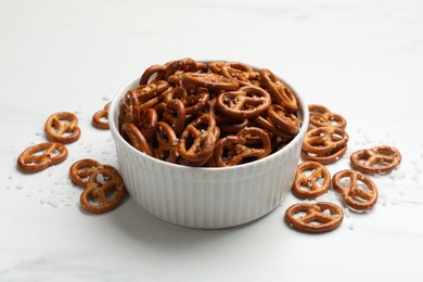 Photo of Tasty pretzel crackers with salt on white table, closeup