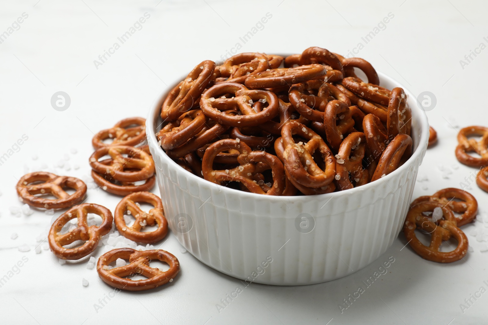 Photo of Tasty pretzel crackers with salt on white table, closeup