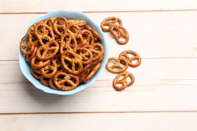 Photo of Tasty pretzel crackers on light wooden table, top view. Space for text