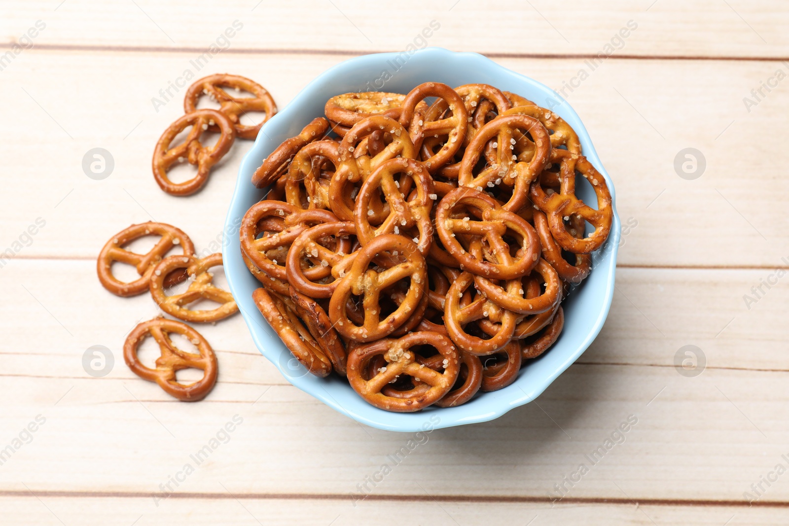 Photo of Tasty pretzel crackers on light wooden table, top view