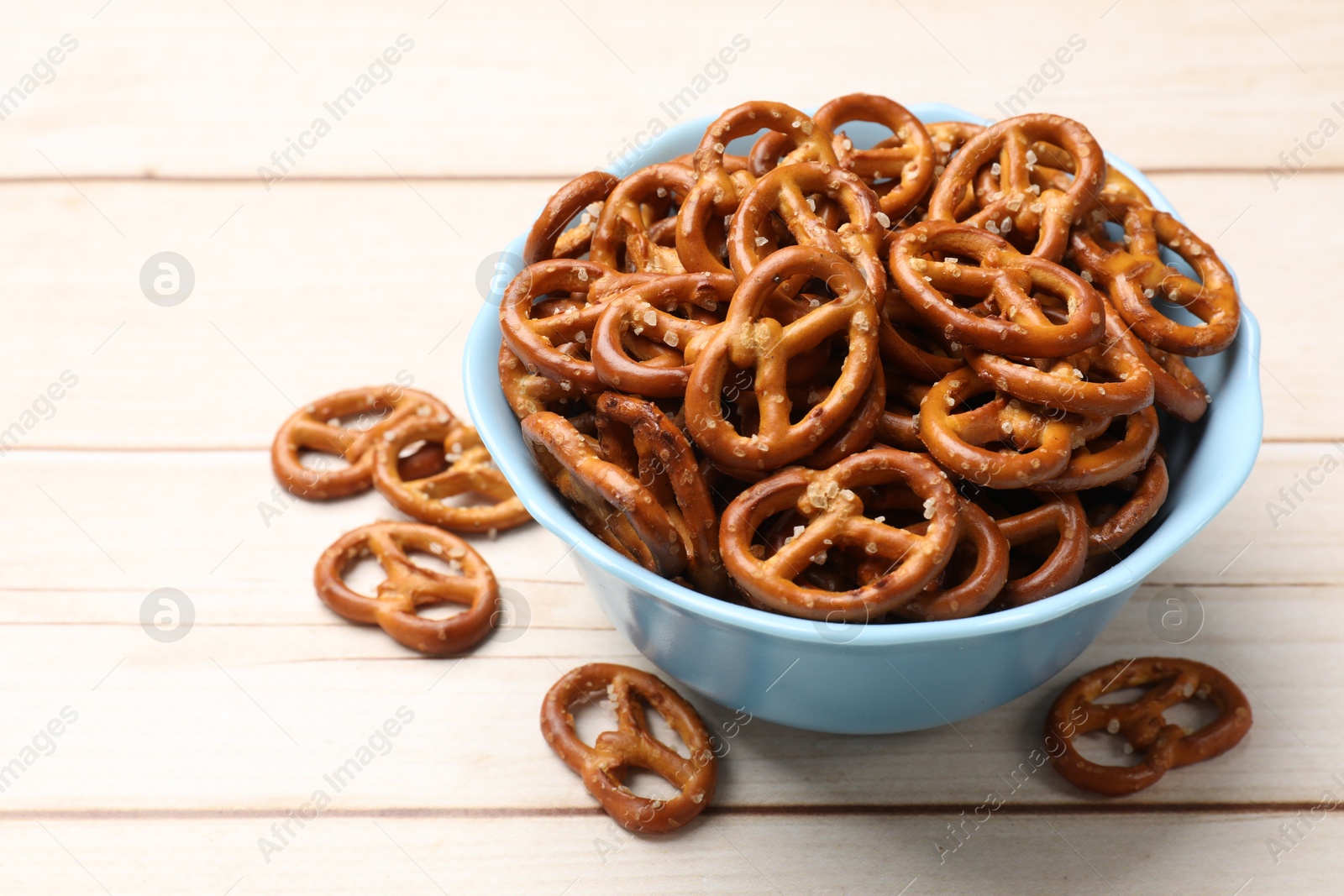 Photo of Tasty pretzel crackers on light wooden table, closeup