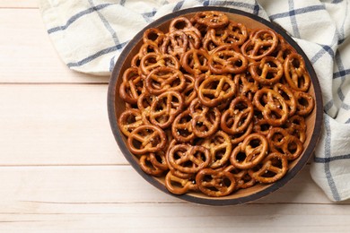 Photo of Tasty pretzel crackers in bowl on light wooden table, top view. Space for text