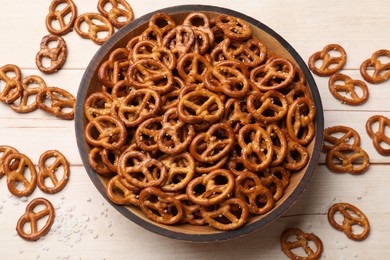 Photo of Tasty pretzel crackers with salt on light wooden table, top view