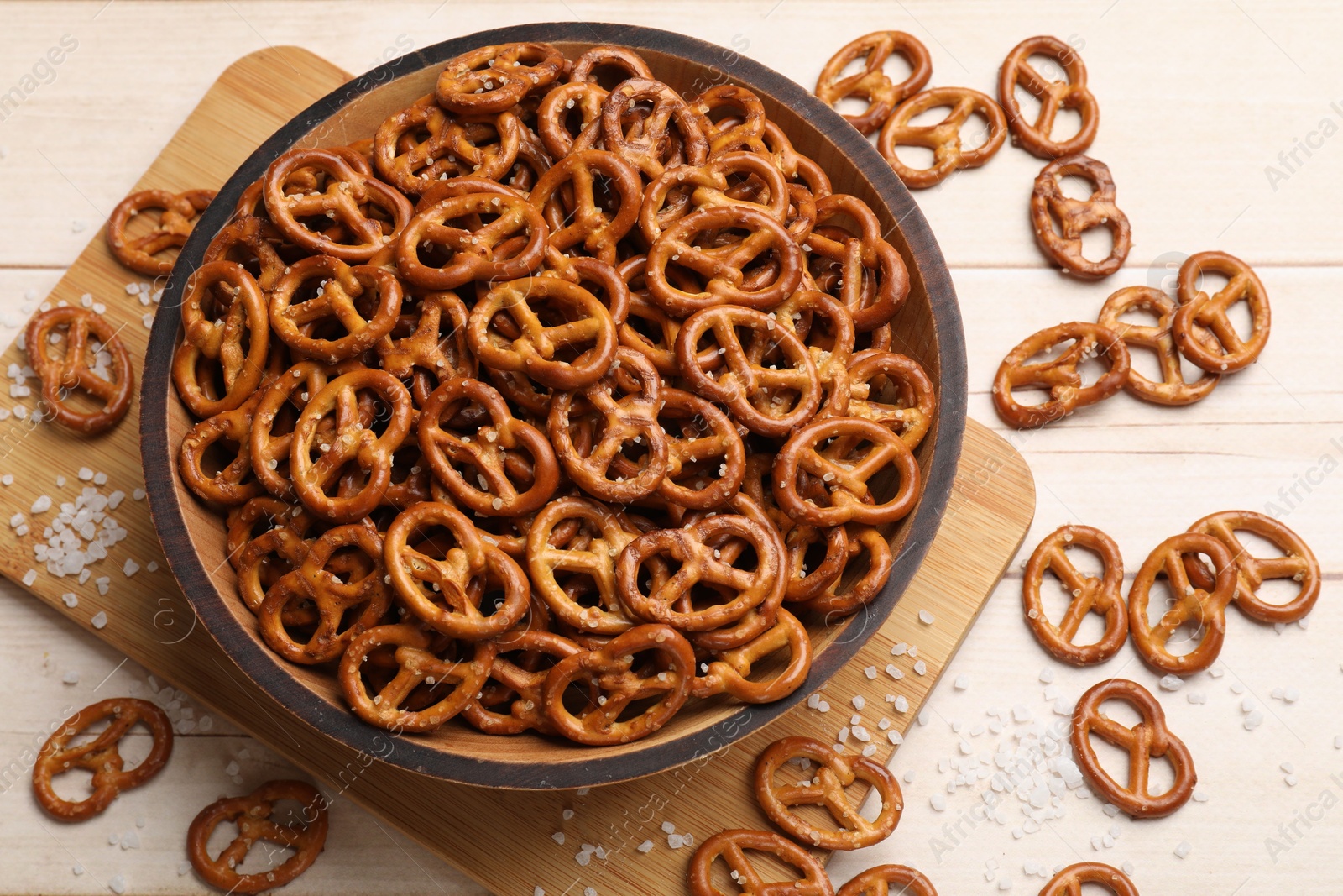 Photo of Tasty pretzel crackers with salt on light wooden table, top view