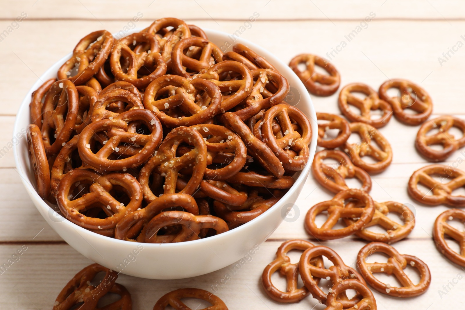 Photo of Tasty pretzel crackers on light wooden table, closeup