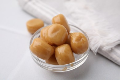 Photo of Tasty hard toffee candies in glass jar on light table, closeup