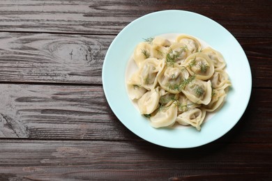 Photo of Delicious pelmeni with dill on wooden table, top view. Space for text