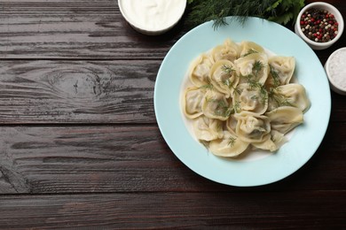 Photo of Delicious pelmeni with dill served on wooden table, flat lay. Space for text