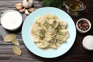 Photo of Delicious pelmeni with dill served on wooden table, flat lay