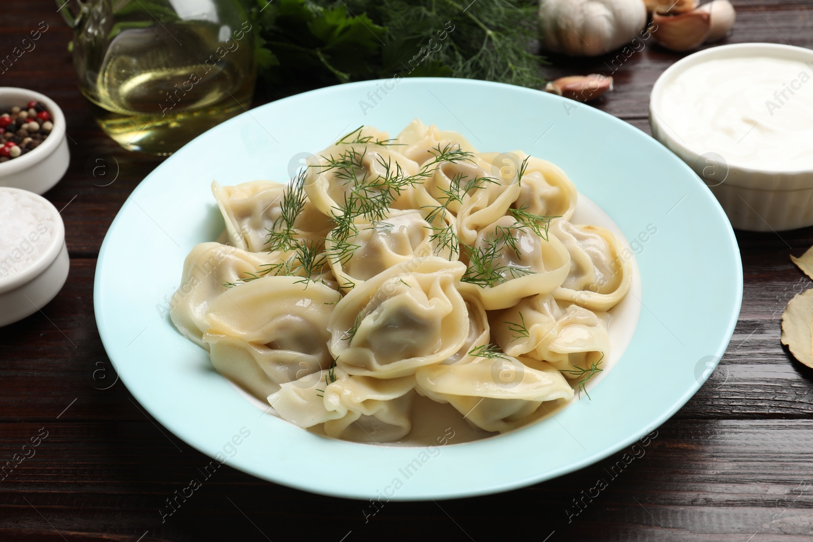 Photo of Delicious pelmeni with dill served on wooden table, closeup