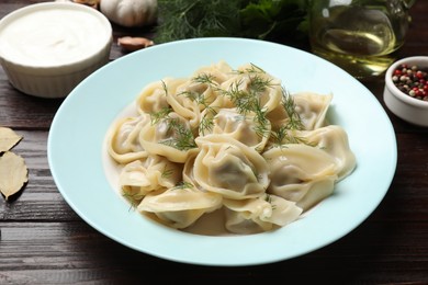 Photo of Delicious pelmeni with dill served on wooden table, closeup