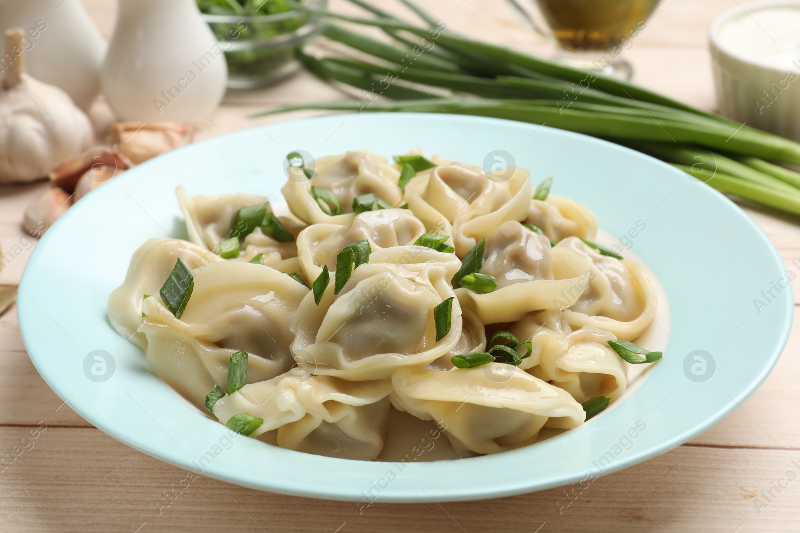 Photo of Delicious pelmeni with green onion served on white wooden table, closeup