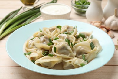 Photo of Delicious pelmeni with green onion served on white wooden table, closeup