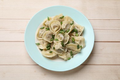 Photo of Delicious pelmeni with green onion on white wooden table, top view