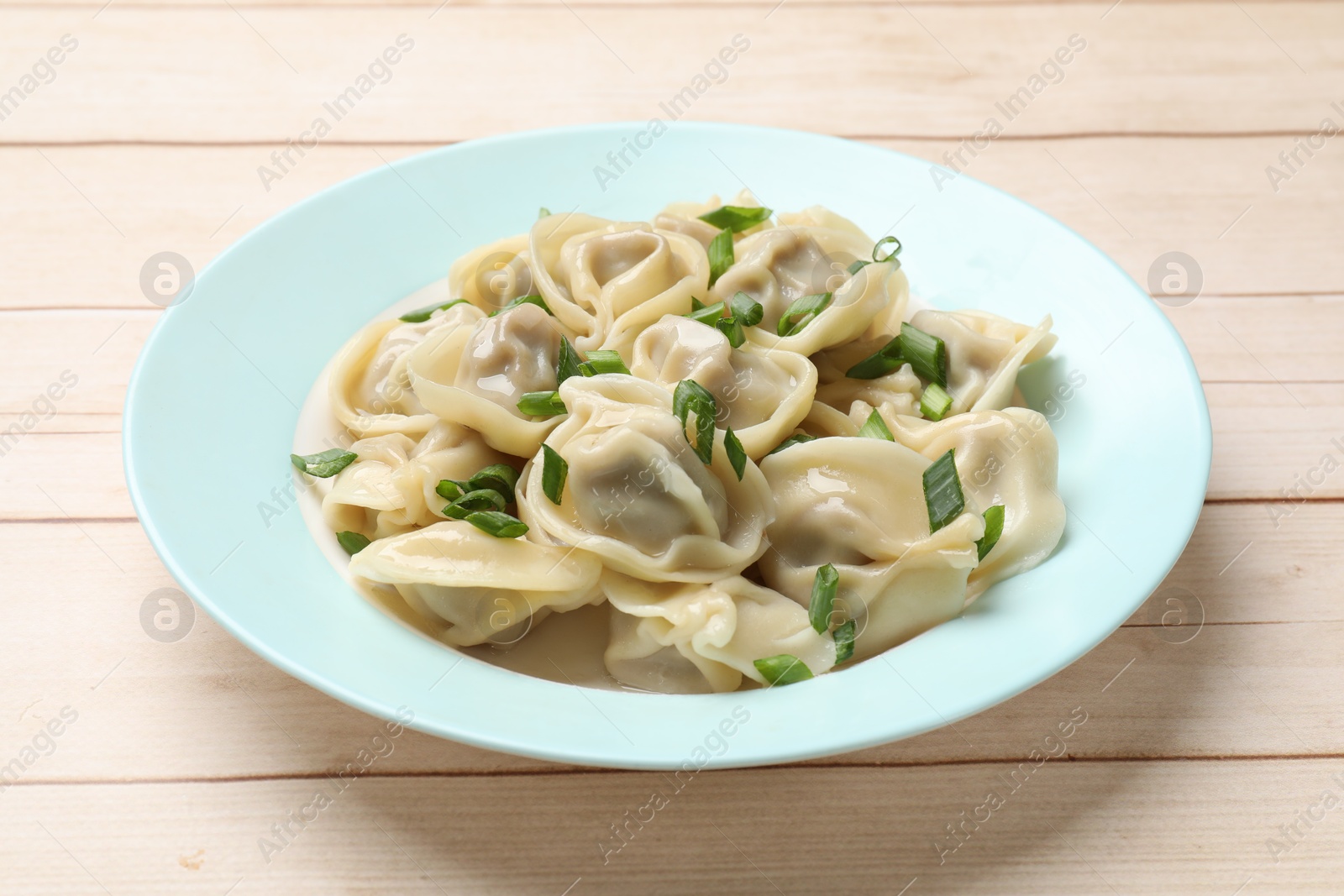 Photo of Delicious pelmeni with green onion on white wooden table