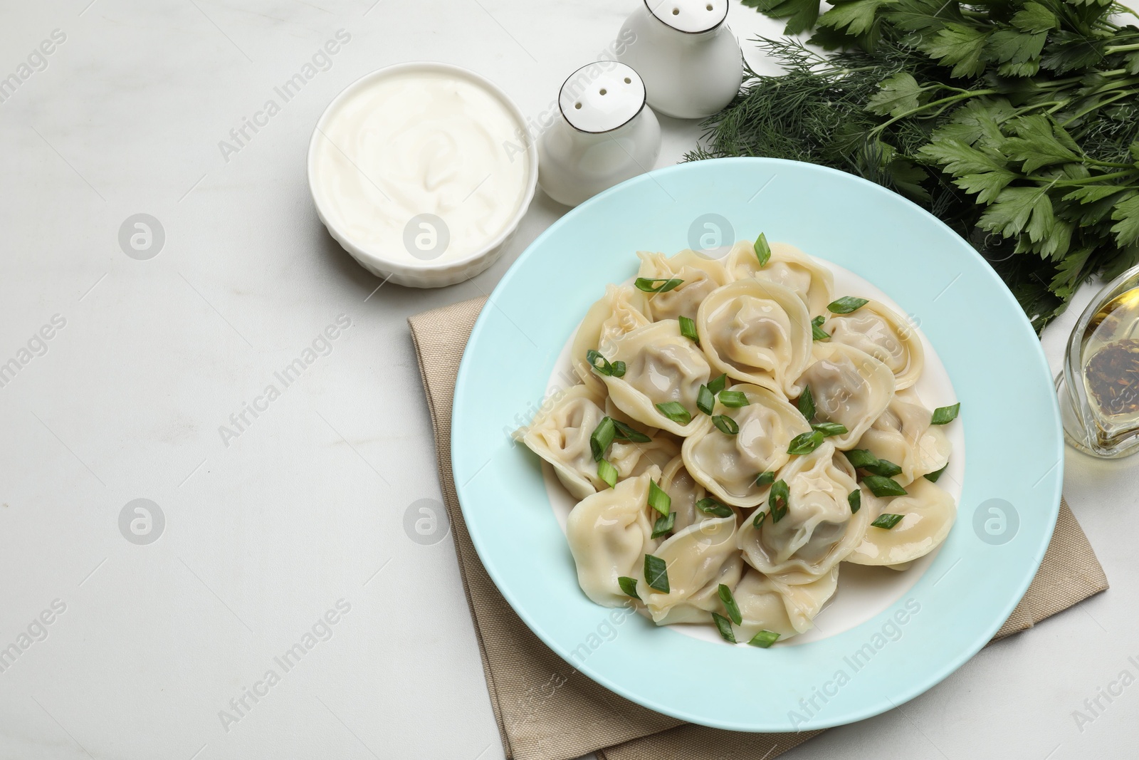 Photo of Delicious pelmeni with green onion served on white table, flat lay