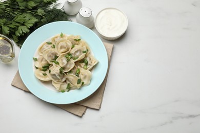 Photo of Delicious pelmeni with green onion served on white marble table, flat lay. Space for text