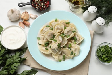 Photo of Delicious pelmeni with green onion served on white table, flat lay