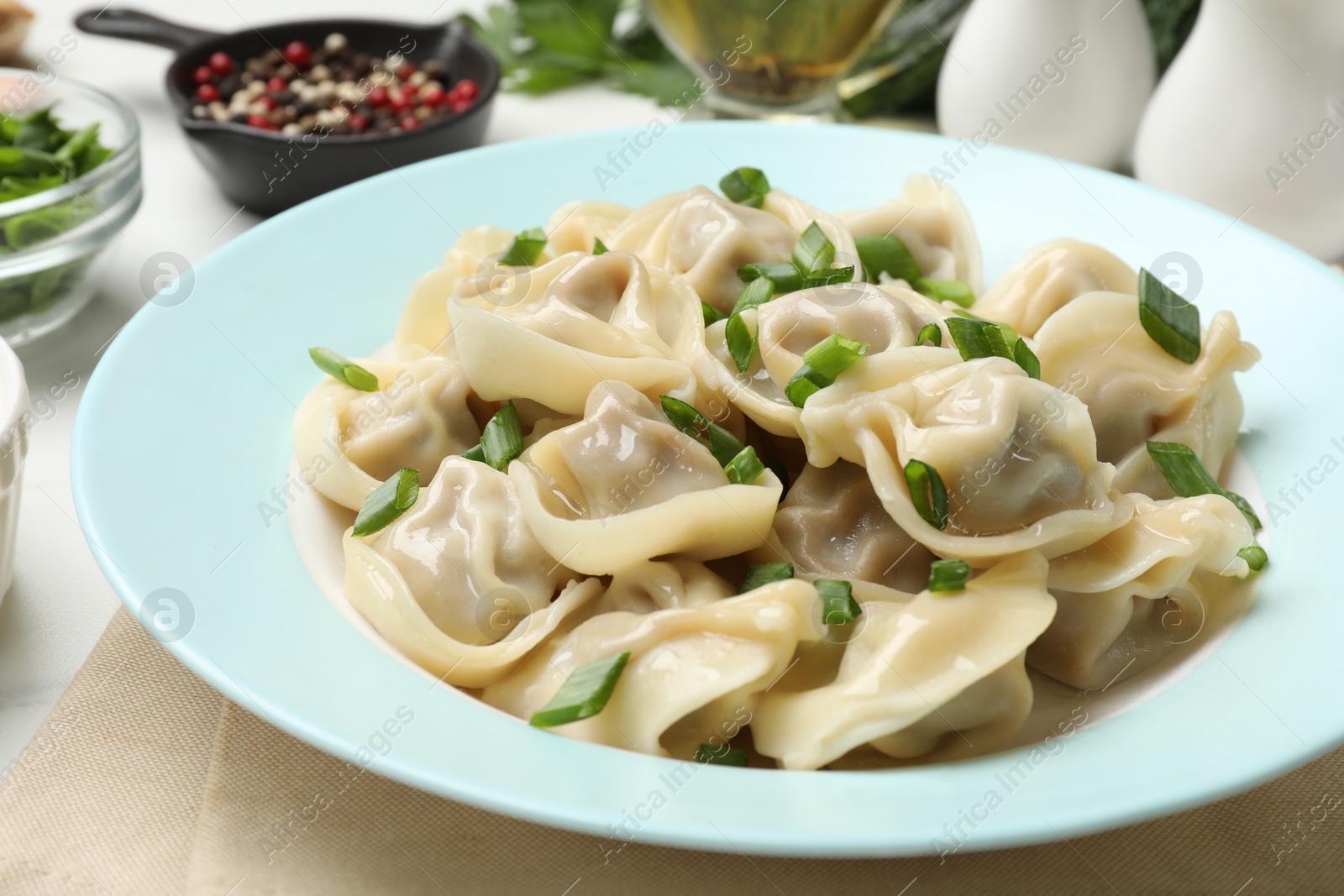 Photo of Delicious pelmeni with green onion served on white table, closeup