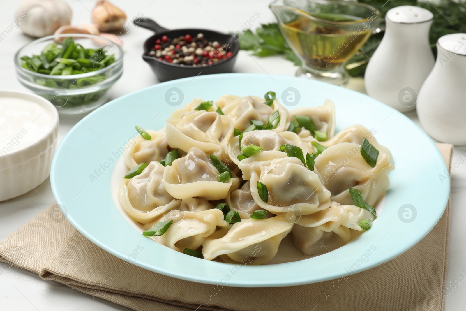 Photo of Delicious pelmeni with green onion served on white table, closeup