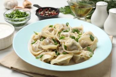 Photo of Delicious pelmeni with green onion served on white table, closeup