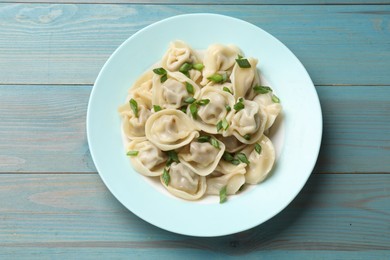 Photo of Delicious pelmeni with green onion on blue wooden table, top view