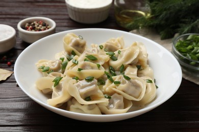 Photo of Delicious pelmeni with green onion served on wooden table, closeup